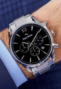 Silver stainless steel chronograph watch with a black dial, silver hour markers, and sub-dials. Features date display and polished accents.