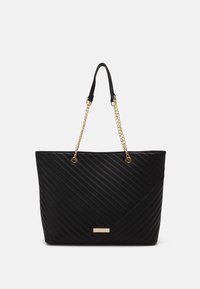 Black tote bag with a quilted design and gold chain handles. Features a rectangular shape and logo detail at the front. Textured surface.