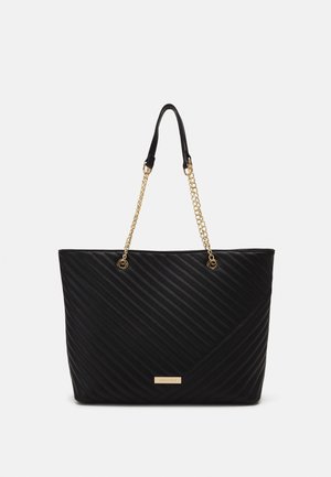 Zwarte totebag met een doorgestikt ontwerp en gouden kettinghandvatten. Heeft een rechthoekige vorm en een logodetail aan de voorkant. Gecorrodeerd oppervlak.