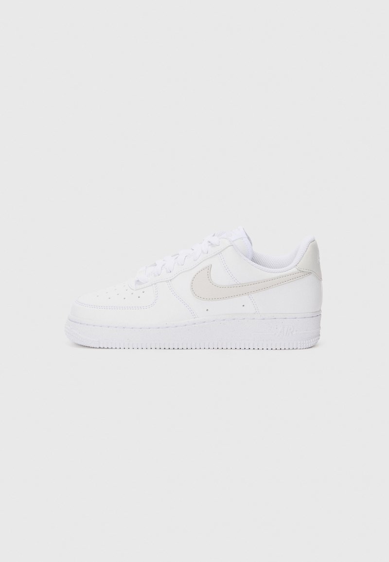 Baskets Nike Air Force 1 blanches avec une tige en cuir lisse, des coutures ton sur ton, une semelle en caoutchouc et un accent de logo beige clair.