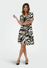 Robe à manches courtes arborant un motif zèbre noir et blanc, taille cintrée et jupe à volants, fabriquée en tissu léger avec une silhouette fluide.