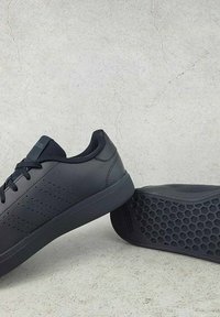 Čierne tenisky s hladkým koženým zvrškom, perforovaným vzorom po boku, plochou gumovou podrážkou a šnurovaním. Šesťuholníkový vzor na podrážke.