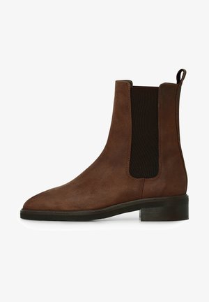 Bottine Chelsea en daim marron avec panneau élastique latéral noir, talon bas et languette à l'arrière.
