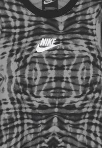 Szary i czarny tank top z efektem tie-dye, z okrągłym dekoltem, z białym logo Nike na środku. Miękka tkanina o fakturowanym wzorze.