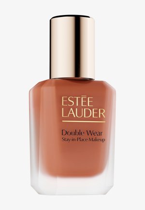 Flacon en verre brun avec une base conique, un bouchon en métal doré et des accents blancs. Présente une étiquette « Estée Lauder Double Wear » en noir.