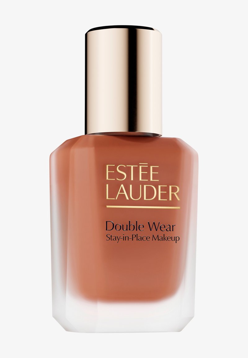 Flacon en verre brun avec une base conique, un bouchon en métal doré et des accents blancs. Présente une étiquette « Estée Lauder Double Wear » en noir.