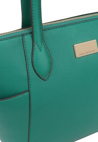 Sac à main en cuir vert avec une surface texturée, quincaillerie dorée et fermeture éclair. Présente une poche avant et des coutures décoratives.