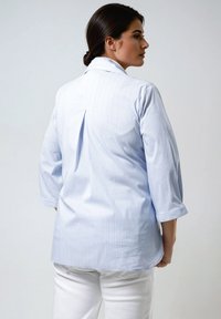 Chemise à rayures bleu clair avec des manches trois-quarts, un pli dans le dos et un ourlet légèrement arrondi. Fabriquée en tissu lisse et léger.