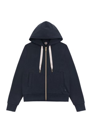 Tmavě modrá mikina na zip s předními kapsami, béžovými šňůrkami a kapucí, s malým kulatým logem poblíž lemu.