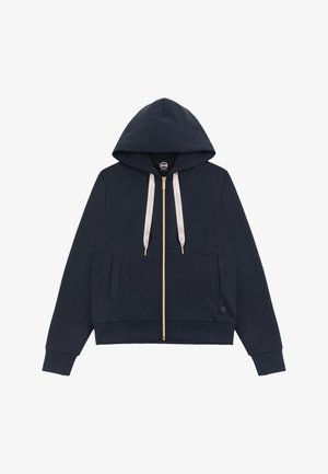 Tmavě modrá mikina na zip s předními kapsami, béžovými šňůrkami a kapucí, s malým kulatým logem poblíž lemu.