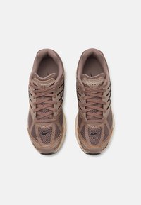 Bruna mesh sneakers med beige accenter, med ett texturerat mönster och svarta ränder. Inkluderar snören och en vadderad krage.