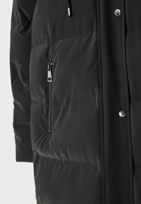 Sort pufferjakke med en glat tekstur, der har en lynlås lomme og trykknapdetaljer langs fronten.