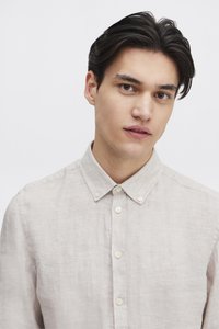 Lysebeige linnedragt med en knap-ned krave, der har en subtil tekstur og seks forreste knapper, egnet til både afslappet og formelt brug.