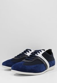 Blå mocka och mesh sneakers med svarta accenter, vit logoband och ljus sula. Har platta snören och en strömlinjeformad design.