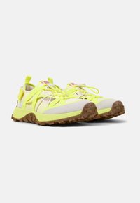 Bright yellow athletic shoes with a mesh and suede upper, textured rubber sole, and strap detailing. Features a secure lace system.