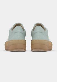 Paire de baskets en daim bleu clair avec des semelles épaisses en caoutchouc marron, vues de dos sur un fond blanc uni.