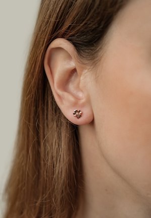 Orecchino a perno a forma di fiore in oro rosa, con cinque petali, di piccole dimensioni, texture lucida, fissato con una chiusura a pressione standard.