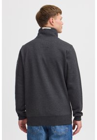 Hanorac din fleece gri închis cu guler înalt, manșete și tiv striate. Prezintă o textură buclată și detalii subtile de design pe spate.