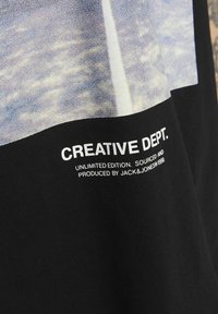 Černé bavlněné tričko s potištěným grafickým motivem v šedých a modrých tónech, se bílým textem "CREATIVE DEPT." a "UNLIMITED EDITION."