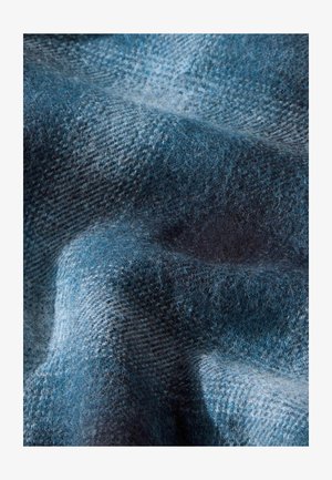 Vuna tkanina sa teksturiranim plavim uzorkom u različitim nijansama, koja stvara suptilan kockasti uzorak i mekan, blago pahuljast površinu.