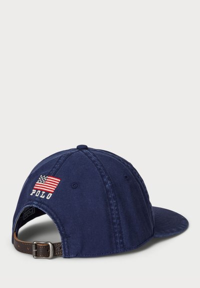 Casquette de baseball bleu marine avec un drapeau américain brodé et "POLO" en blanc. Matériau en coton ; fermeture à sangle en cuir ajustable à l'arrière.