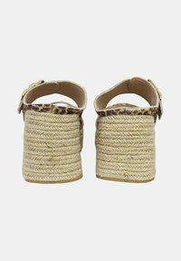 Zoccoli espadrilles con base in juta intrecciata testurizzata, dotati di una fascia con stampa leopardata e chiusura con fibbia. Palette di colori naturali.