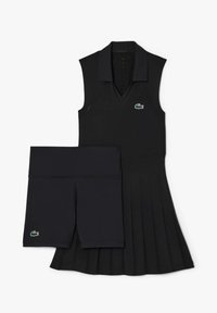 Abito nero senza maniche con scollo a V, gonna plissettata e logo Lacoste, abbinato a pantaloni corti neri con un logo simile e vita elasticizzata.