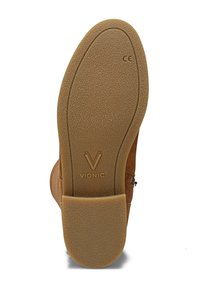 Semelle extérieure en caoutchouc marron avec surface texturée, présentant un motif circulaire et un logo Vionic en relief près du talon. Forme ovale avec une légère courbure.