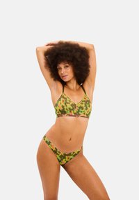 Groene camouflage bikini set met een triangle bralette met dunne bandjes en een lage taille broek, geaccentueerd met roze details en bloemenpatronen.