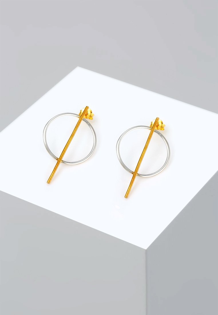 Orecchini geometrici in oro e argento con un cerchio e una barra diritta che attraversa il centro. Finitura lucida.