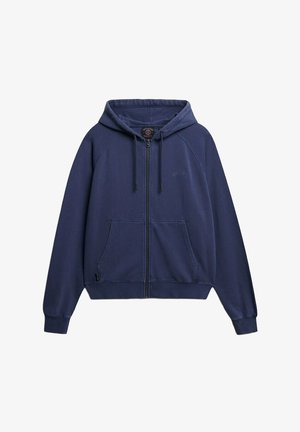 Sudadera con cremallera en navy de tejido suave, con capucha ajustable, dos bolsillos frontales y puños acanalados. Presenta un logo en relieve sobre el bolsillo izquierdo.