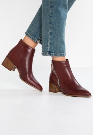 Enkellaarsjes van bruin leer met een rits aan de zijkant en lage houten hakken, gedragen bij cropped blauwe spijkerbroek.