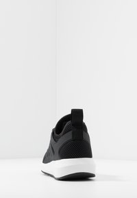 Černá sportovn�í obuv s síťovaným svrškem, polstrovaným límcem, poutkem na patě a bílou podrážkou s texturovaným vzorem.