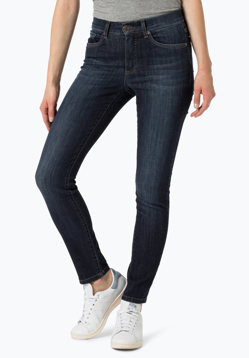 Donkerblauwe skinny jeans met een gladde denimtextuur, een vijf-pocketontwerp en een middelhoge taille. Gecombineerd met witte sneakers.