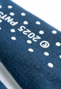 Fascia in tessuto blu navy con pois bianchi. Presenta un materiale a maglia testurizzato e la scritta stampata "2025 PNT". Design di accessorio classico.