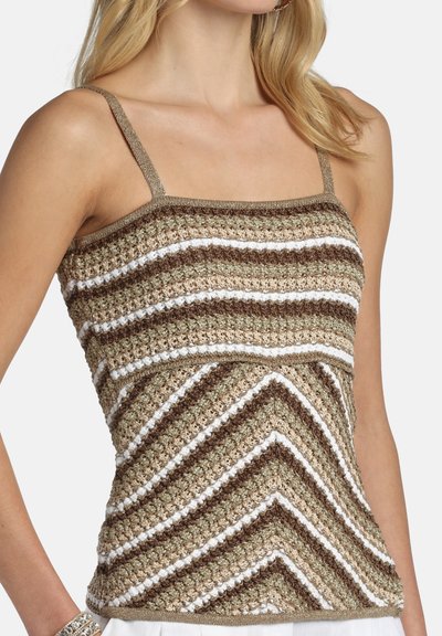 Femme portant un haut sans manches en crochet avec des rayures en chevrons marron, crème et blanc et de fines bretelles, visible du cou aux hanches.