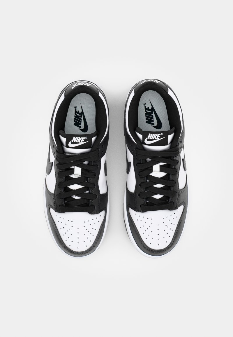 Nike Sneaker mit einem Obermaterial aus schwarzem und weißem Leder, perforiertem Zehenbereich, schwarzen Schnürsenkeln und einer grauen Innensohle mit dem Nike-Logo.