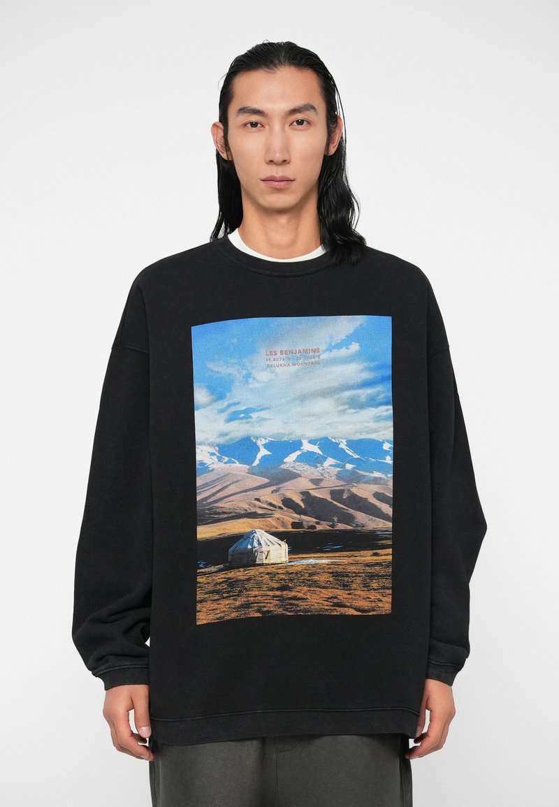 Felpa nera con una grande stampa grafica di un paesaggio con montagne e un yurt. Design a maniche lunghe e collo rotondo.