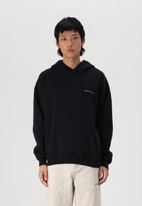 Sweatshirt negru cu glugă, fabricat dintr-un amestec de bumbac, cu buzunar frontal și logo brodat. Croială lejeră, cu manșete și tiv ribbate.