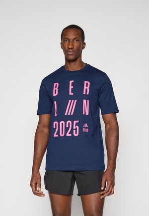Navy blue cotton T-shirt featuring bold pink text: "BERLIN 2025." Short sleeves and crew neck design with a logo at the bottom.