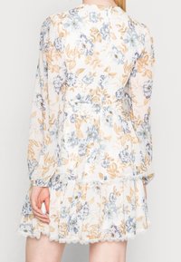 Blommönstrad klänning i lätt material, med blå och orange blommor, långa ärmar, en figurnära midja och spetsdetaljer vid fållen.