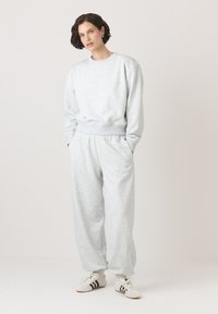 Szary sweter i pasujące dresowe spodnie wykonane z miękkiego materiału. Strój ma luźny krój, ściągacze przy mankietach i elastyczny pas.