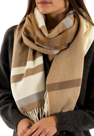 Écharpe tissée en tons beige, crème et gris, avec un motif écossais et des bords frangés. Texture douce et design surdimensionné pour plus de chaleur.