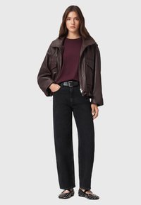 Brun läderjacka med två framfickor, bourgognefärgad skjorta, svarta vida jeans och svarta ballerina skor med vita nitar. Enkelt, modernt design.