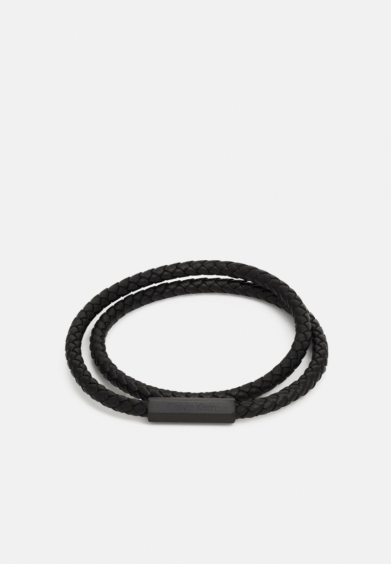 Mustmust mustriba nahkakeed, millel on sile, ristkülikuline metallist klamber Calvin Klein logo ja kaks silmust reguleeritava sobivuse jaoks.