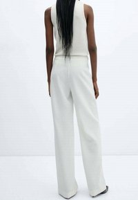 Witte wijde broek met een gladde textuur, een op maat gemaakte pasvorm en een hoge taille, gecombineerd met een lichtgekleurde mouwloze top.