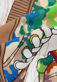 Mintás szövet tereptarka mintával, barnával, zölddel és kékkel. Fehér zsinórokat és varrási részleteket tartalmaz.