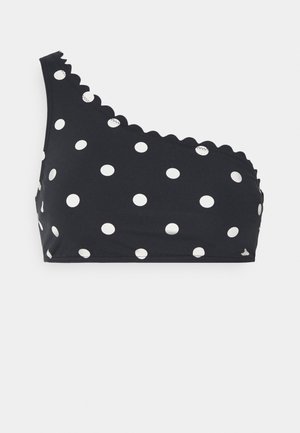 Bikini top noir à épaule dénudée avec des pois blancs, featuring des bords festonnés et des accents de boutons. Tissu lisse et extensible.