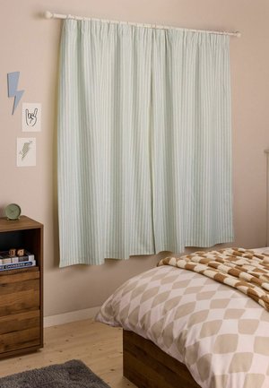Des rideaux rayés vert clair suspendus à une tringle au-dessus d'une fenêtre à côté d'une table de nuit en bois avec une horloge et des livres dans une chambre.