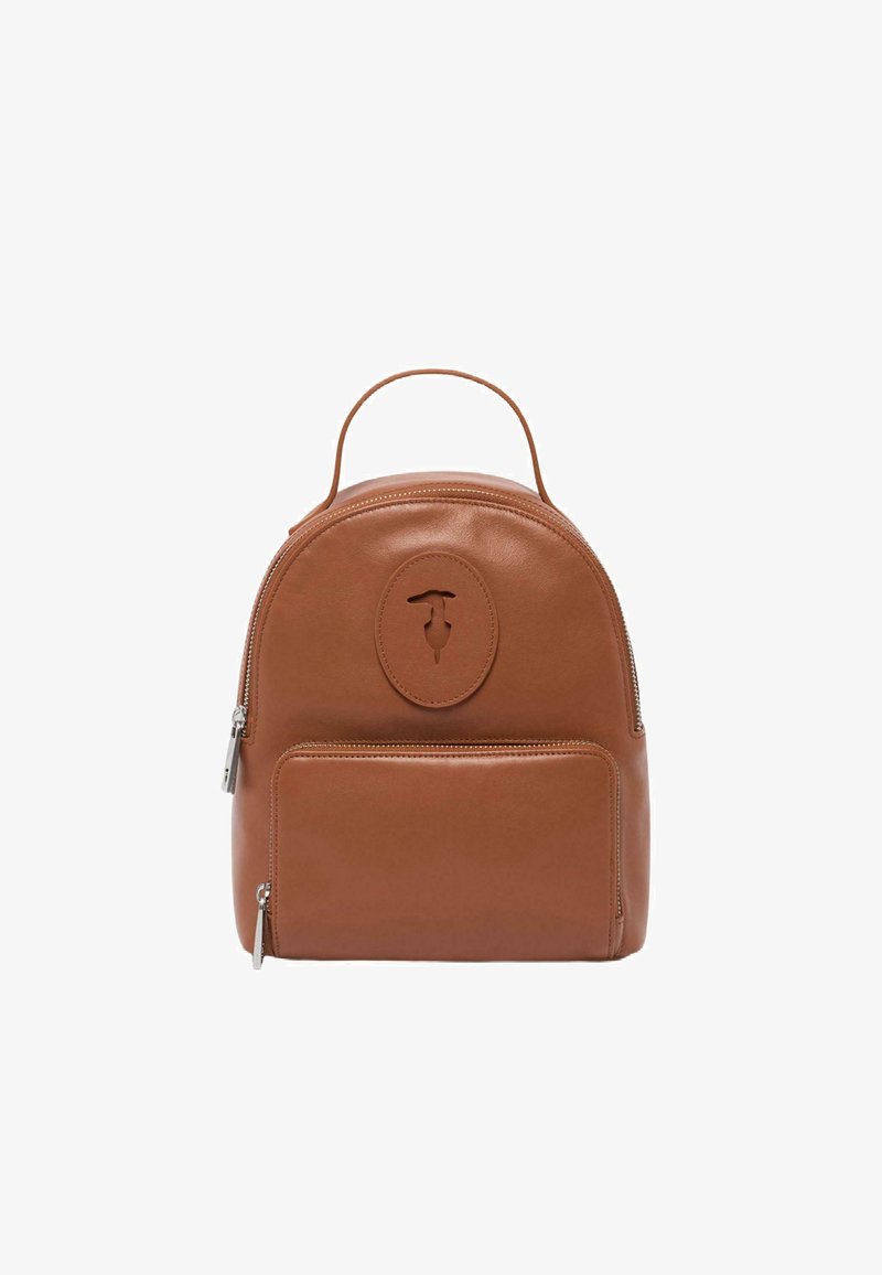 Mochila de cuero marrón con forma redondeada, bolsillo con cremallera en la parte frontal y un acento de logotipo circular. Cuenta con un asa superior para llevar.